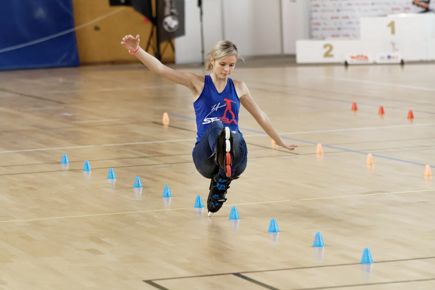 Klaudia Hartmanis réalise une figure de slalom en roller entre des plots colorés.